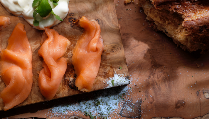 Oak smoked salmon resting on a serving board with fresh sea salt nearby for seasoning.